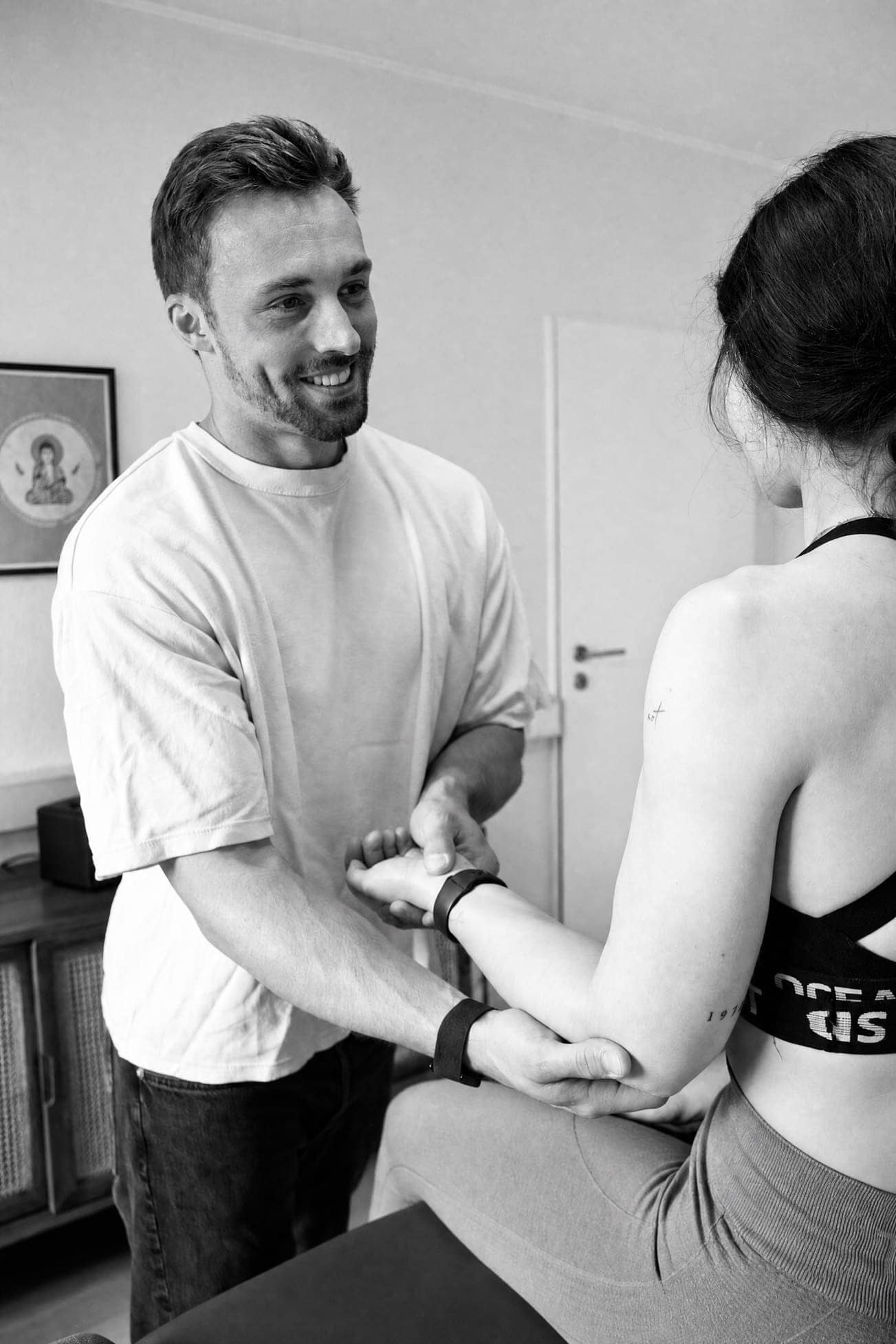 Therapeut bei der Behandlung einer Patientin in der Physiotherapie, freundliche Atmosphäre.