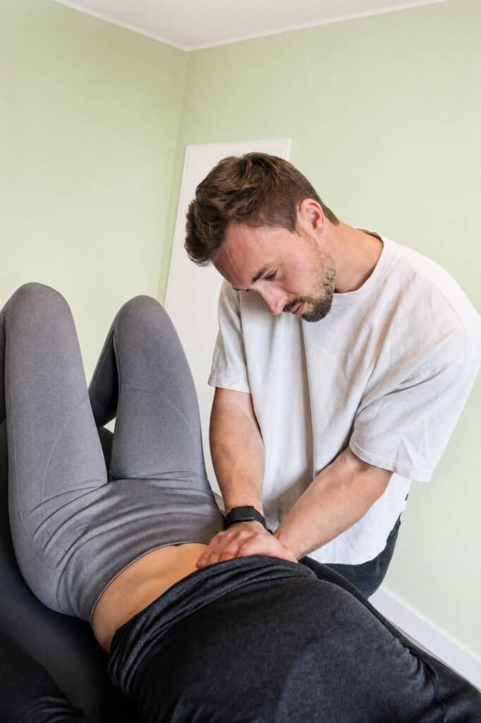 Therapeut bei manueller Therapie an Patient im Behandlungsraum.