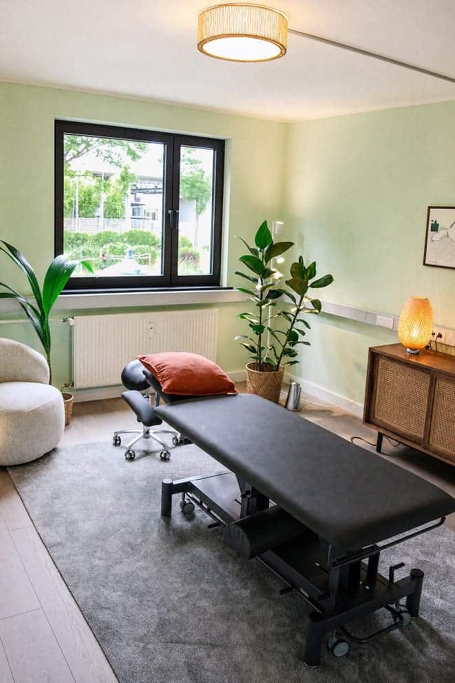Behandlungsraum mit Behandlungsliege, Pflanzen und natürlichem Licht bei Wissler Therapie.